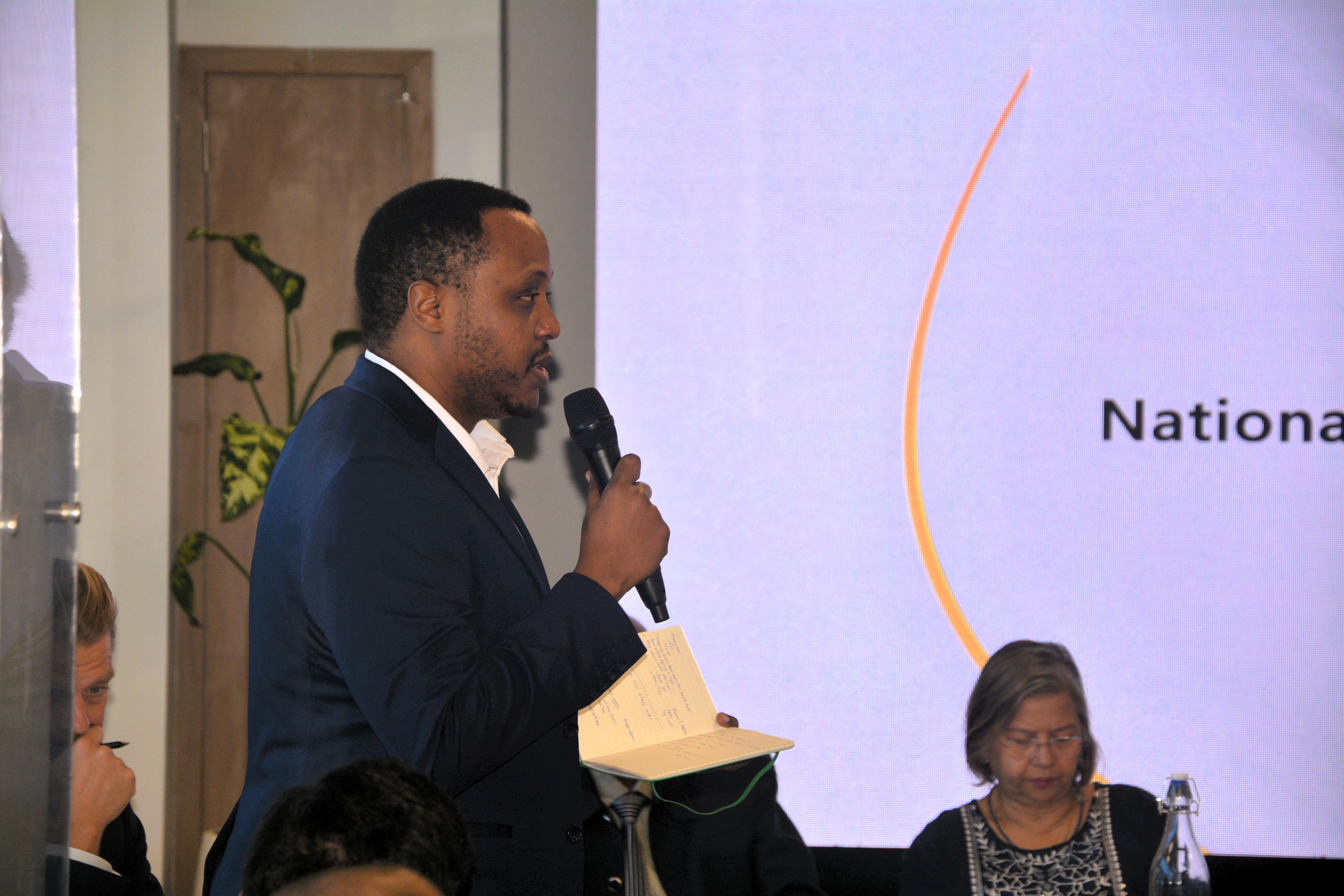 NGO representative speaking into a microphone during a consultation on the National Multidimensional Poverty Index at The Docks, Mauritius